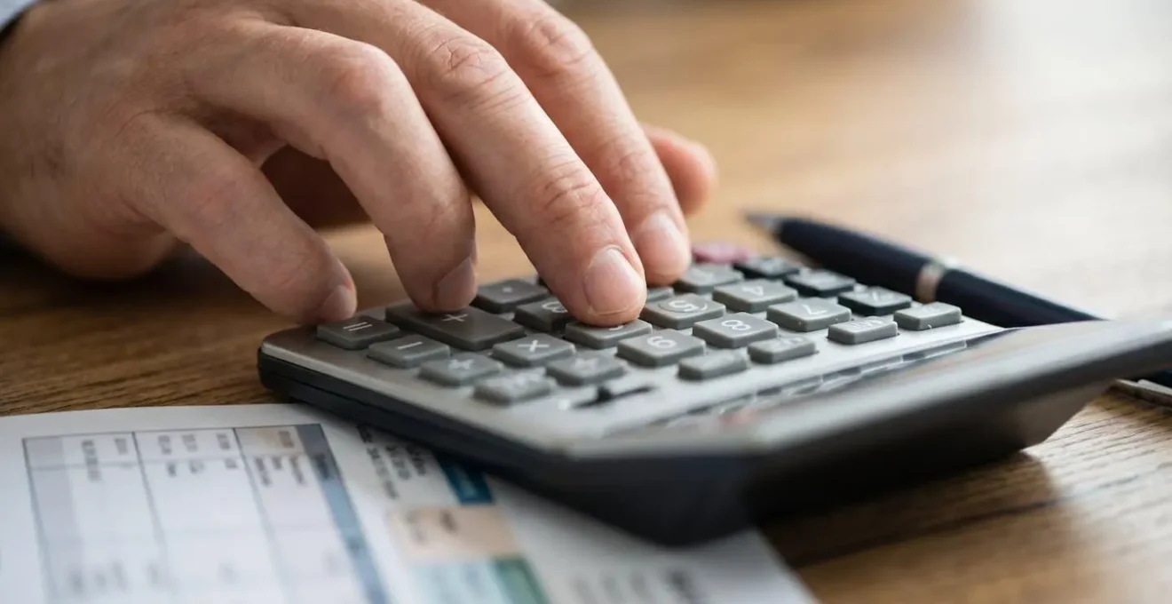 Gros plan sur des mains effectuant un calcul de remboursement santé avec calculatrice et facture médicale